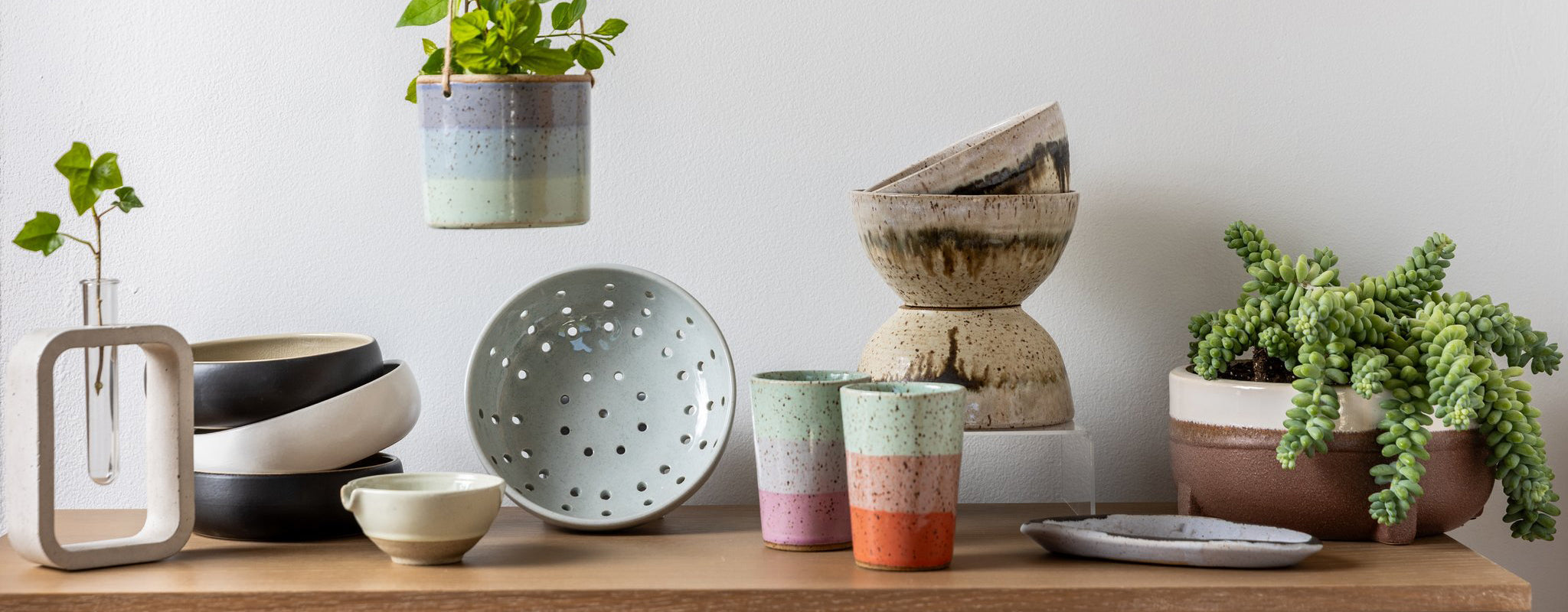 Khepri Collective's collection of handmade ceramic wares are arranged beautifully on a tabletop: planters, bowls, cups, trays and more.