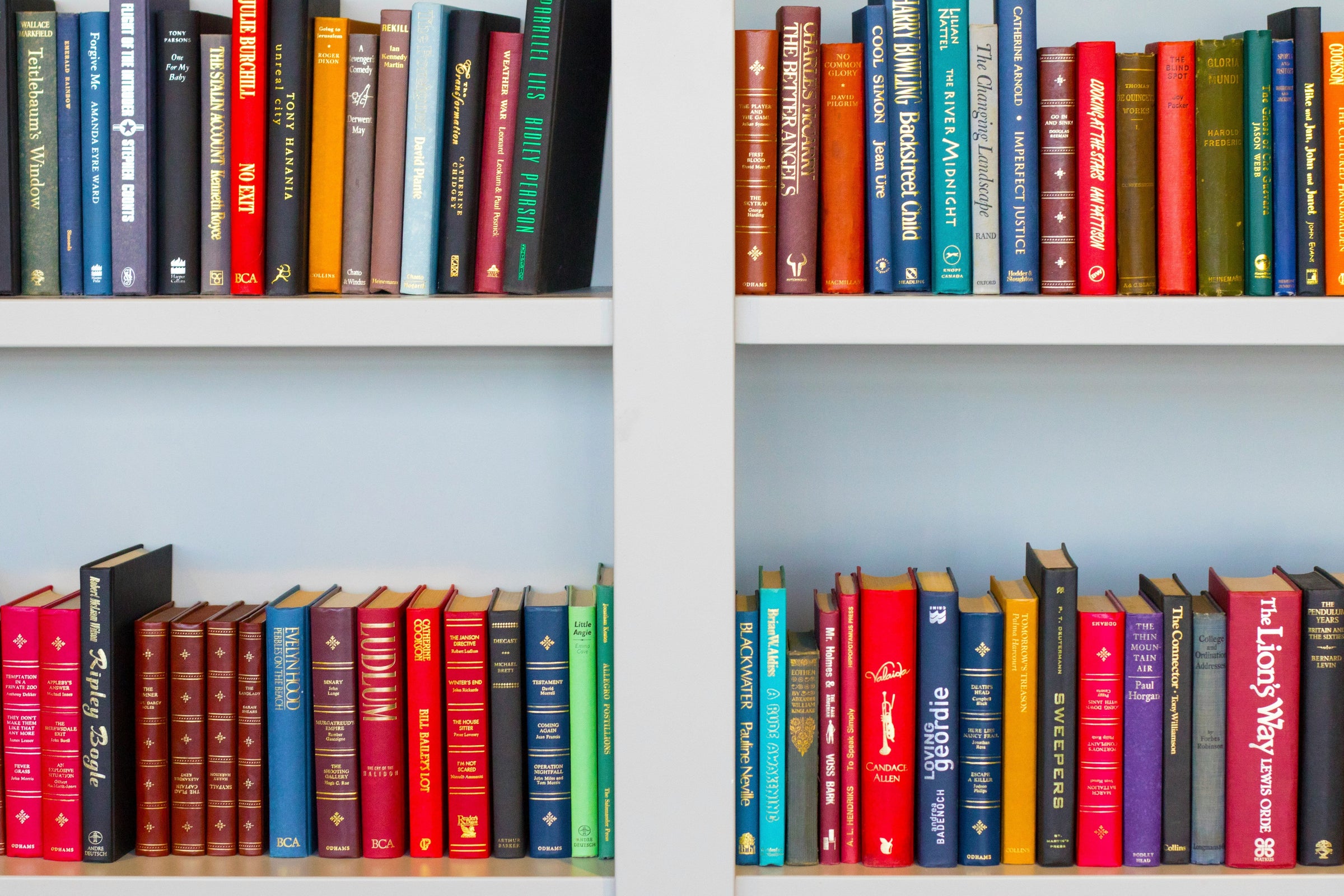 White bookshelves full of neat books in many colors and sizes.