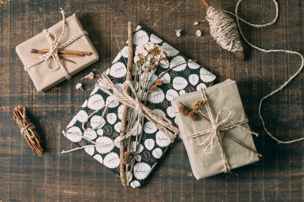 wooden table with wrapped gifts in green paper with flowers and Kraft paper with twin.  